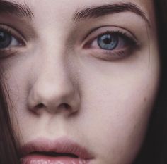 a close up of a woman's face with blue eyes