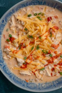 a blue and white bowl filled with soup covered in cheese