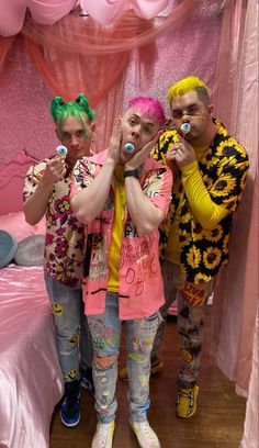 three people standing in front of a bed with pink and yellow decorations on the walls