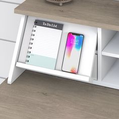 a desk with a notepad, pen and phone on it next to a shelf