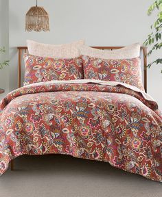 a bed covered in a red paisley print comforter set with pillows and pillow cases