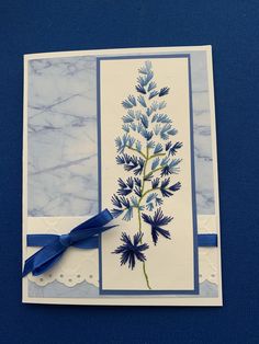 a blue and white greeting card with a flower on the front, tied in a blue ribbon