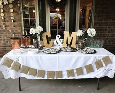 a white table topped with lots of food and desserts next to a brick building