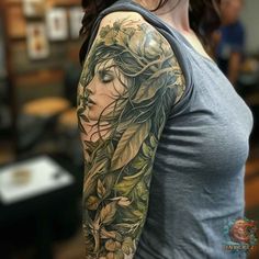 a woman's arm with flowers and leaves on it