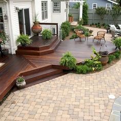 a deck with steps leading up to it and potted plants on the other side