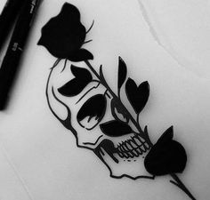 a black and white photo of a skull with flowers on it's head, next to two markers