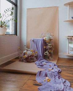 a room with flowers on the floor next to a large piece of paper that has been folded down