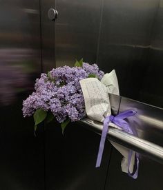 a bouquet of purple flowers sitting on top of a metal bench next to a wall