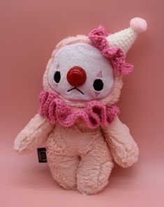 a pink teddy bear with a red nose wearing a scarf