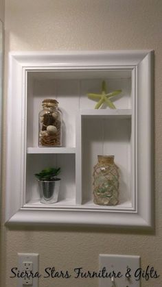 there is a white shelf with two jars and a starfish on it in the bathroom