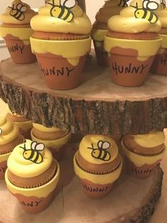 cupcakes with yellow frosting and bees on them sitting on a tree stump