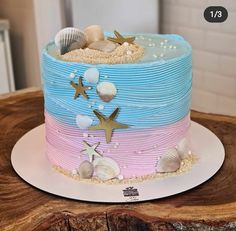 there is a blue and pink cake with sea shells on the top, along with starfish