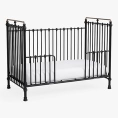 an iron crib with white sheets on the bottom and black metal rails, against a white background