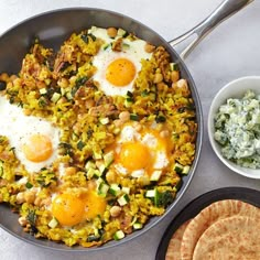 two fried eggs are on top of some rice and cucumbers in a pan