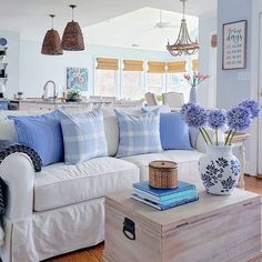 a white couch with blue and white pillows in a living room next to a coffee table