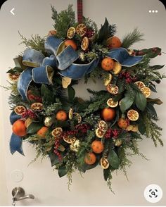 a christmas wreath with oranges and pomegranates hanging on a wall