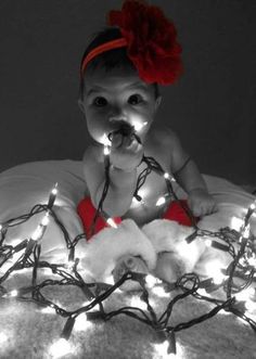 a baby is sitting on a bed with christmas lights