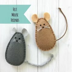 two felt mouses sitting next to each other on top of a white wooden surface