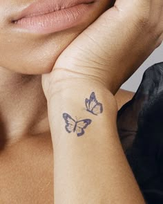 a woman with a butterfly tattoo on her left wrist and right hand behind her head