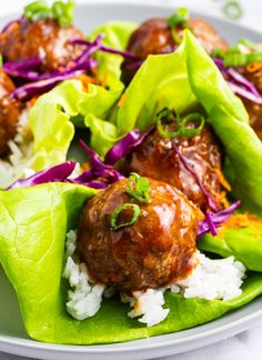 some meatballs and rice are in lettuce wraps on a plate with coleslaw