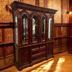 a large wooden china cabinet in a room with wood paneling on the walls and floor