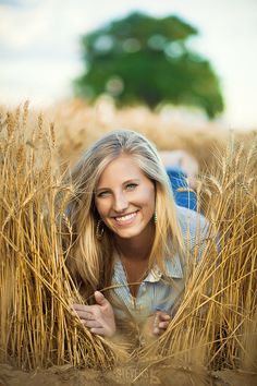 a woman is smiling in the middle of a wheat field with her hands behind her head