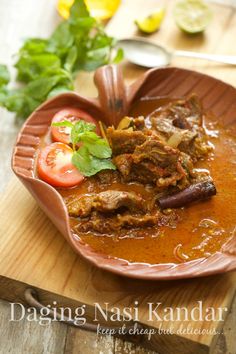 a bowl filled with meat and vegetables on top of a wooden cutting board