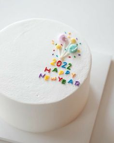 a birthday cake decorated with colorful letters and sprinkles on a white surface