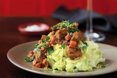 a white plate topped with meat and veggies next to a glass of wine