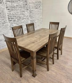 a wooden table and chairs in front of a brick wall with a clock on it