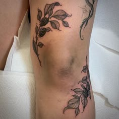 a woman's leg with flowers and leaves tattoo on the side of her thigh