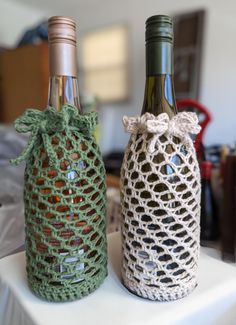 two crocheted wine bottles sitting on top of a table