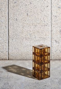 a cube shaped object sitting on top of a cement floor next to a wall with no one in it