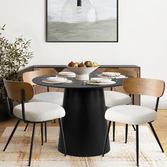 a dining room table with four chairs and a bowl of fruit on the plate in front of it