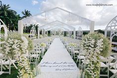 an outdoor wedding setup with white flowers and greenery on the aisle, surrounded by chairs