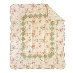 a quilted blanket with pink flowers and green trimmings on the bottom half