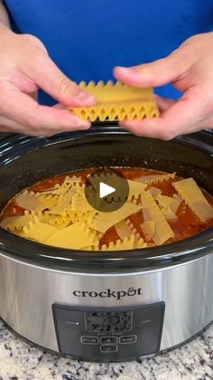 two hands are pulling pasta out of the crock pot