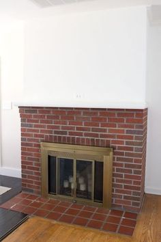 an empty room with a brick fireplace and wood flooring on the side, in front of a white wall