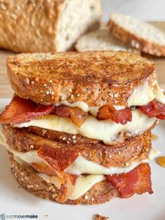 a sandwich with bacon and cheese is on a white plate next to some toasted bread