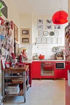 a kitchen with red cabinets and pictures on the wall