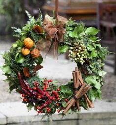 a christmas wreath hanging from a pole with cinnamons, apples and greenery on it