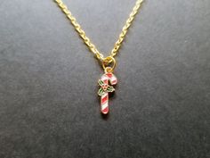 "Scary Aliens' Candy Cane Necklace is 18\" inches long and sturdily constructed of gold chain and a gold enamel candy cane pendant. Lobster clasp closure. You'll love its: 🎄 Sturdy handmade construction 🎄 Durable metal hardware 🎄 Handmade in California and sold by the artist (me!) 👽 Check out my shop, ScaryAliens.etsy.com, for more colors and designs!" Scary Alien, Xmas Jewelry, Gold Candy, Christmas Necklace, Bow Jewelry, Wedding Jewellery Necklace, Gold Enamel, Metal Hardware, Holiday Christmas