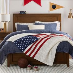 a bed with an american flag comforter on top of it and two basketballs in the foreground