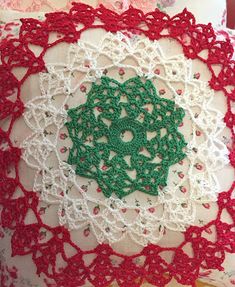 a crocheted pillow with a green and white doily on the front cover