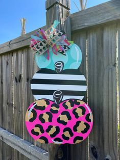 a wooden sign with leopard print on it hanging from a fence next to a gate