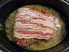 bacon is being cooked in an iron skillet on the stove top with seasoning