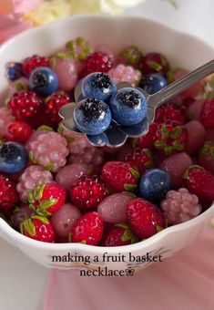 blueberries, raspberries and other berries in a white bowl with a spoon