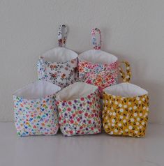 six small baskets are lined up against the wall, each with different designs on them