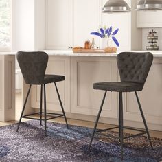 two chairs sitting on top of a rug next to a kitchen counter with an island