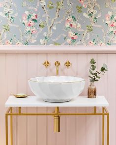 a white bowl sink sitting on top of a table next to a vase with flowers